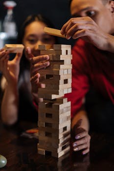 A couple enjoying a game of Jenga indoors, building blocks in a strategic and fun setting.