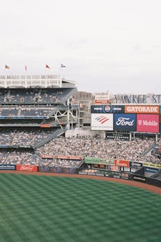 A vibrant daytime scene of Yankee Stadium filled with spectators and vibrant signage.